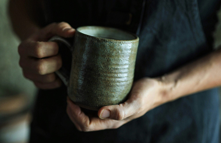 Potter holding a pottery mug.